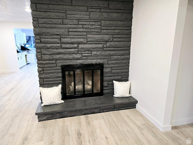 room details with baseboards, wood finished floors, and a stone fireplace