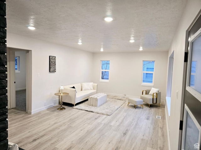 living room featuring recessed lighting, a textured ceiling, baseboards, and wood finished floors
