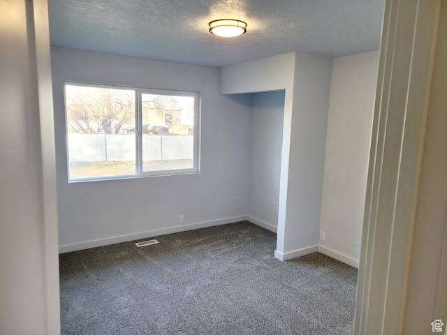 carpeted spare room with visible vents, a textured ceiling, and baseboards