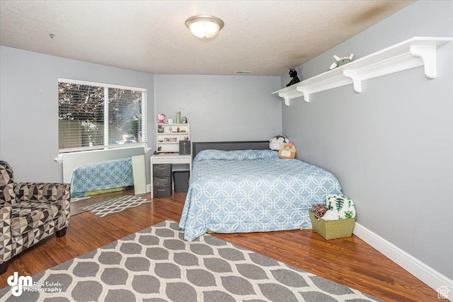 bedroom with wood-type flooring and a textured ceiling