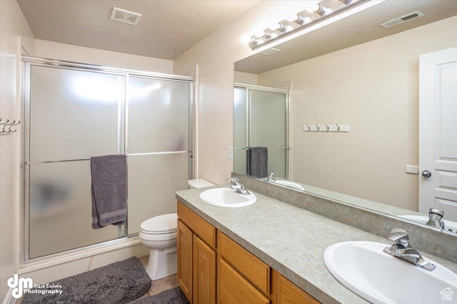 bathroom featuring a textured ceiling, vanity, toilet, and walk in shower