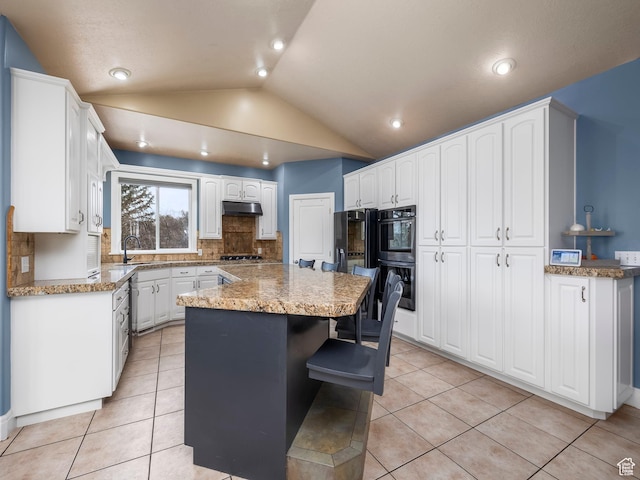kitchen with double oven, light tile patterned flooring, a center island, sink, and white cabinetry