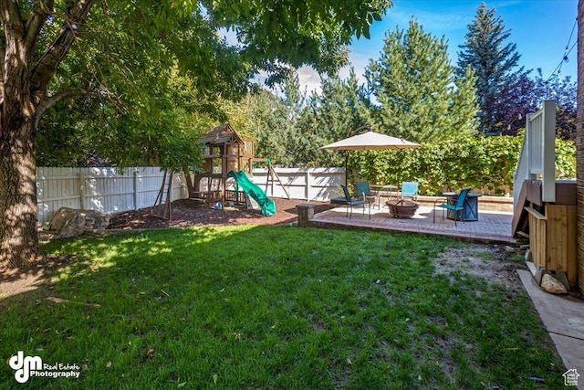 view of yard featuring a patio, a playground, and a fire pit