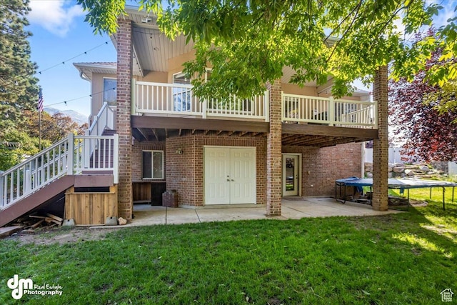 rear view of property featuring a yard, a trampoline, and a patio