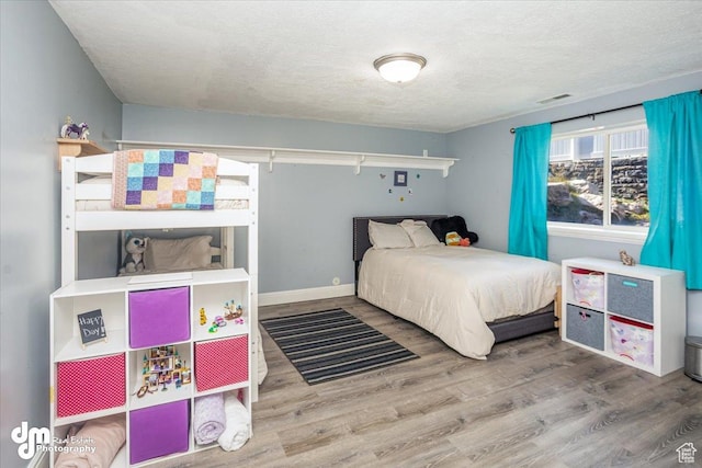 bedroom with hardwood / wood-style floors and a textured ceiling