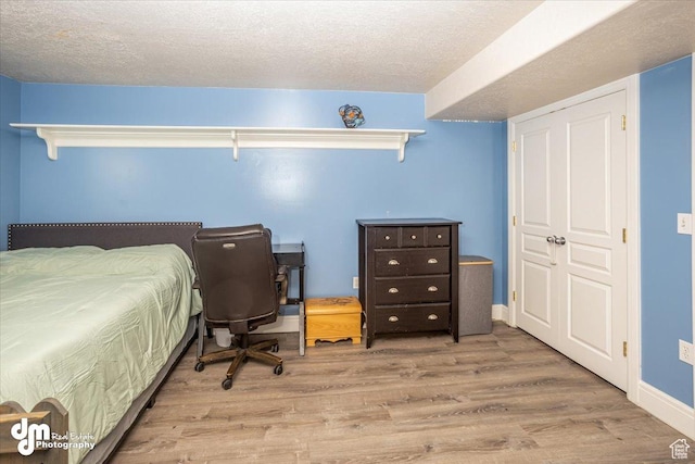 bedroom with light hardwood / wood-style flooring and a textured ceiling