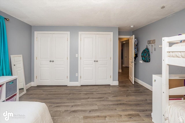 bedroom with hardwood / wood-style floors, multiple closets, and a textured ceiling