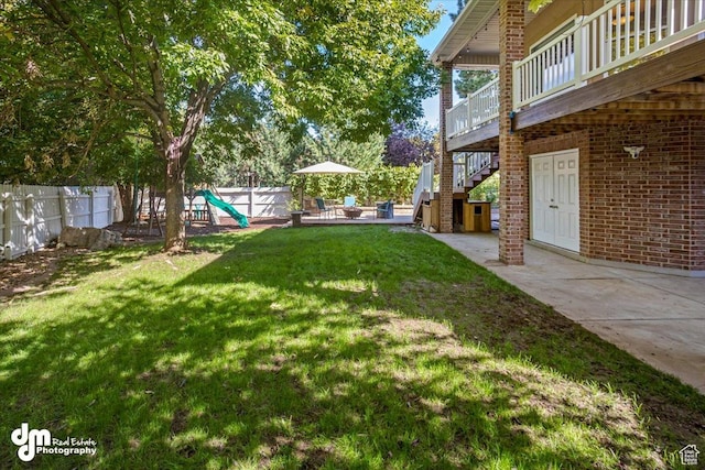 view of yard with a deck, a patio, and a playground
