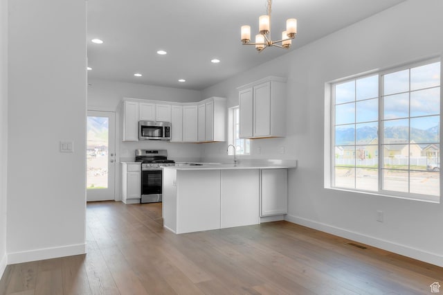kitchen featuring appliances with stainless steel finishes, baseboards, light countertops, white cabinets, and a chandelier