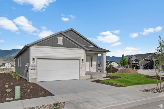 view of front of house with driveway, a mountain view, a garage, board and batten siding, and a front yard