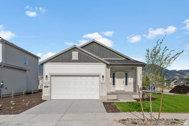 view of front facade with driveway, stone siding, a garage, a mountain view, and a front lawn