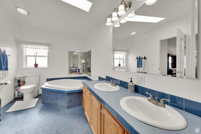 bathroom featuring a skylight, healthy amount of natural light, a garden tub, and toilet
