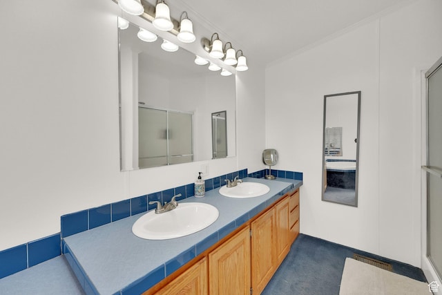 bathroom with double vanity, a shower stall, ornamental molding, and a sink
