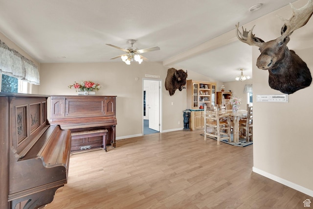 living area featuring light wood finished floors, ceiling fan with notable chandelier, baseboards, and vaulted ceiling with beams