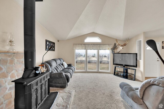 living room featuring a wood stove, lofted ceiling, and carpet floors