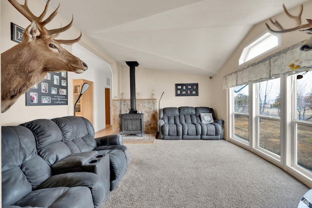 carpeted living area featuring a wood stove and lofted ceiling