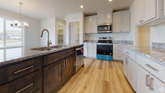 9270 N 5600 W Unit 7, Elwood, UT 84337 - kitchen with a sink, appliances with stainless steel finishes, light wood-type flooring, light stone countertops, and pendant lighting