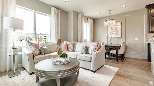 living room featuring a notable chandelier, plenty of natural light, and light hardwood / wood-style flooring