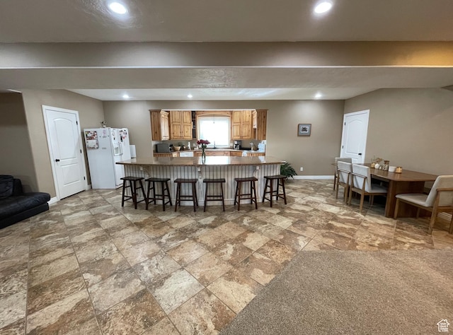 kitchen with white refrigerator with ice dispenser and a breakfast bar