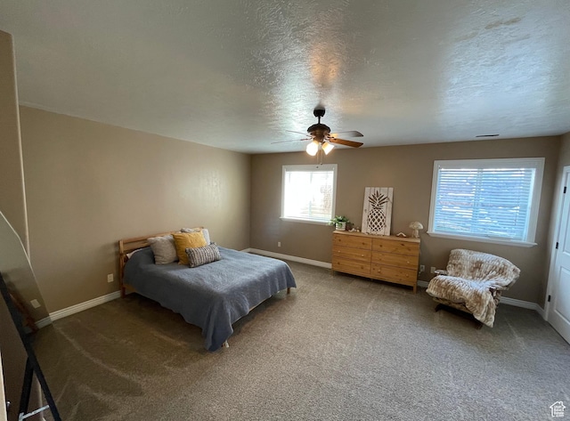 carpeted bedroom featuring ceiling fan and a textured ceiling