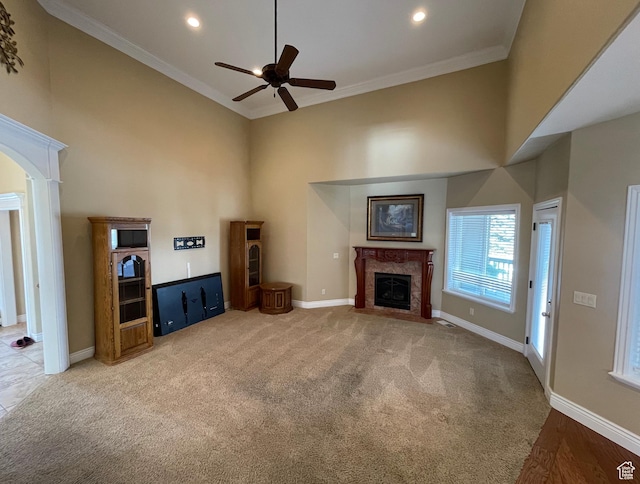 living room featuring light carpet, crown molding, a high end fireplace, and a towering ceiling