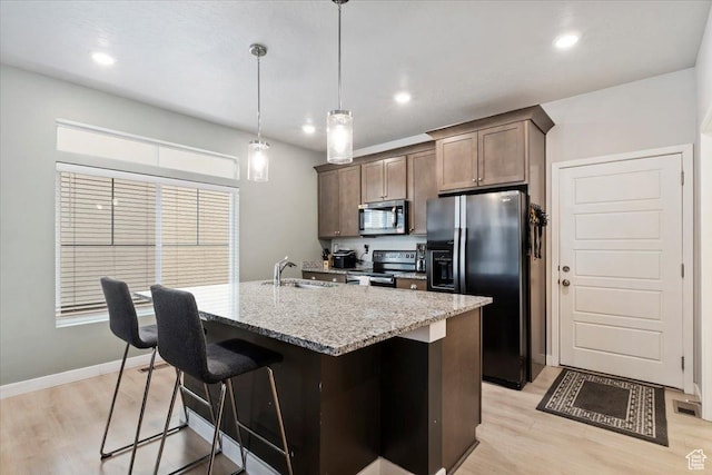 214 E Allegheny Pl S, Saratoga Springs, UT 84045 - kitchen featuring stainless steel appliances, light wood-style floors, light stone countertops, a center island with sink, and recessed lighting