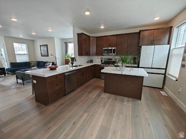 3469 S Bellrock Pl E Unit 5, South Salt Lake, UT 84115 - kitchen featuring kitchen peninsula, appliances with stainless steel finishes, dark brown cabinetry, and light hardwood / wood-style flooring