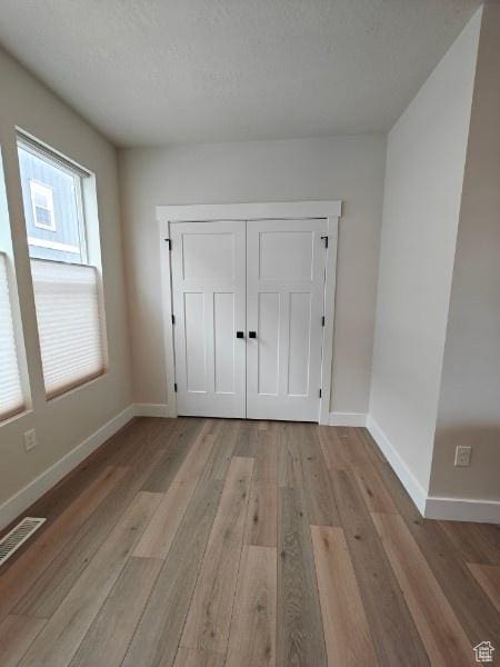 3469 S Bellrock Pl E Unit 5, South Salt Lake, UT 84115 - unfurnished bedroom with light hardwood / wood-style flooring, a textured ceiling, and a closet