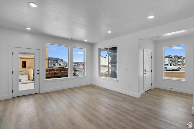 interior space with recessed lighting, baseboards, a textured ceiling, and light wood finished floors