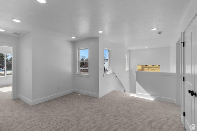 carpeted empty room with visible vents, baseboards, and a healthy amount of sunlight