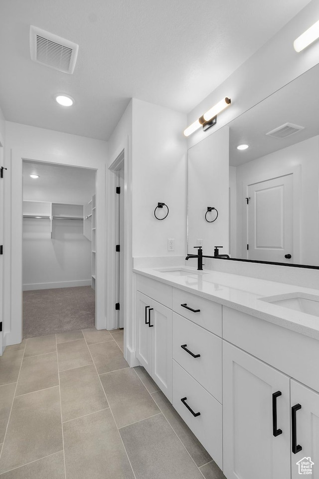 full bathroom with a sink, visible vents, a spacious closet, and double vanity