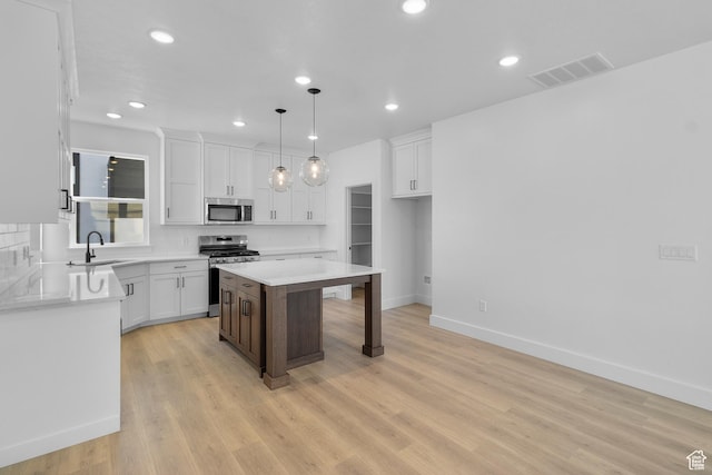 kitchen featuring visible vents, white cabinetry, a sink, appliances with stainless steel finishes, and a kitchen bar