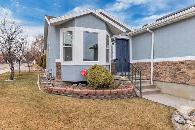 12972 S Cactus Berry Dr, Riverton, UT 84096 - view of exterior entry with stone siding, a yard, and stucco siding