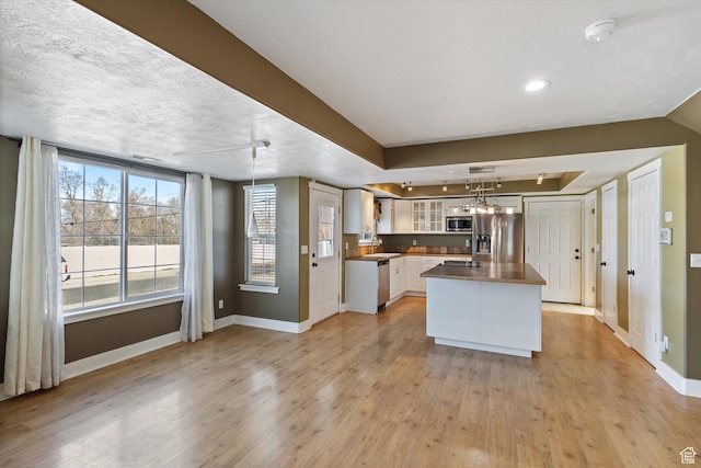 kitchen with baseboards, white cabinets, light wood-style flooring, glass insert cabinets, and appliances with stainless steel finishes