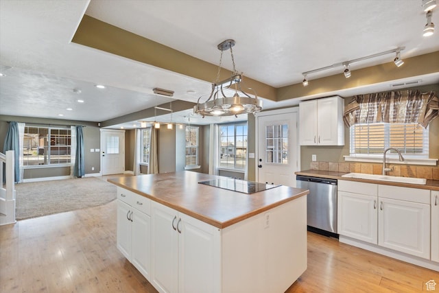 kitchen featuring open floor plan, black electric cooktop, stainless steel dishwasher, light wood-style floors, and a sink