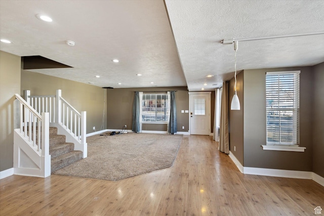 foyer entrance with baseboards, wood finished floors, stairs, a textured ceiling, and recessed lighting
