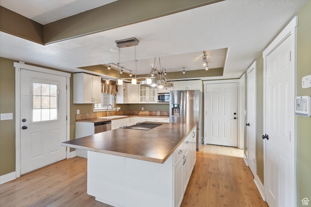 kitchen with stainless steel appliances, light wood-type flooring, a sink, and white cabinets
