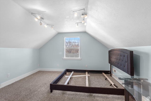 interior space featuring track lighting, baseboards, vaulted ceiling, and a textured ceiling