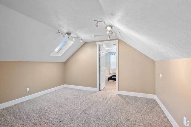 bonus room with lofted ceiling with skylight, carpet, baseboards, and a textured ceiling
