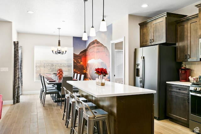 334 N 2020 W, Hurricane, UT 84737 - kitchen with light hardwood / wood-style flooring, stainless steel appliances, dark brown cabinetry, pendant lighting, and a center island