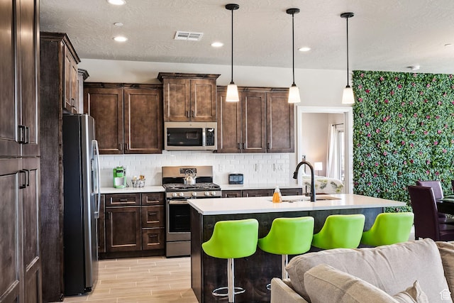 334 N 2020 W, Hurricane, UT 84737 - kitchen featuring an island with sink, sink, backsplash, appliances with stainless steel finishes, and pendant lighting