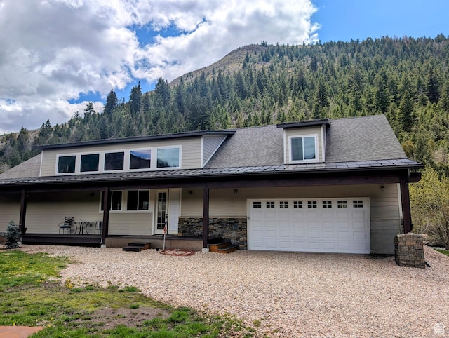 2326 Country Rd, Kamas, UT 84036 - view of front of property featuring a mountain view, a view of trees, a porch, gravel driveway, and an attached garage