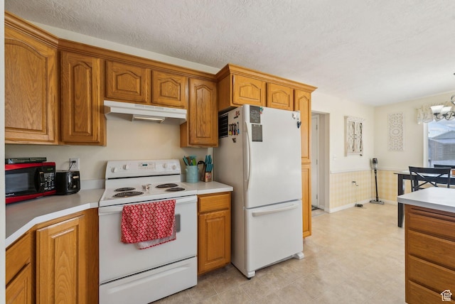 kitchen featuring a notable chandelier, white appliances, and a textured ceiling