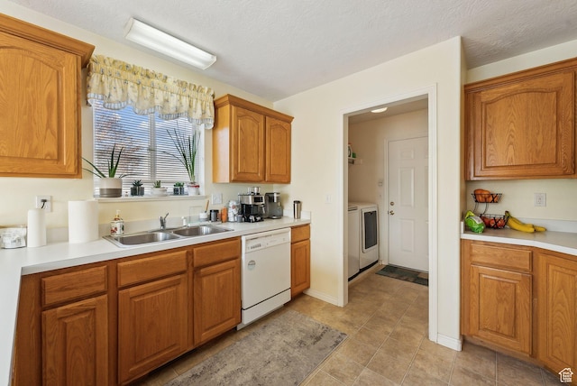 kitchen featuring sink, white dishwasher, a textured ceiling, and washer / clothes dryer