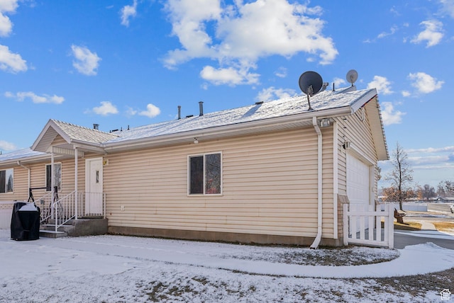 snow covered back of property featuring a garage