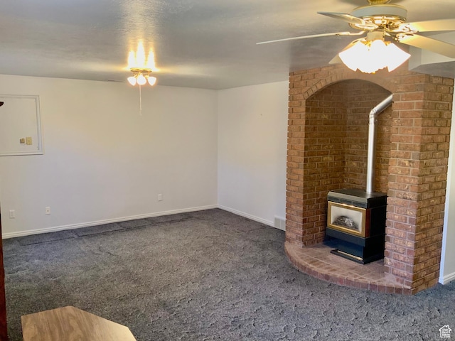 unfurnished living room with a wood stove, carpet, and ceiling fan