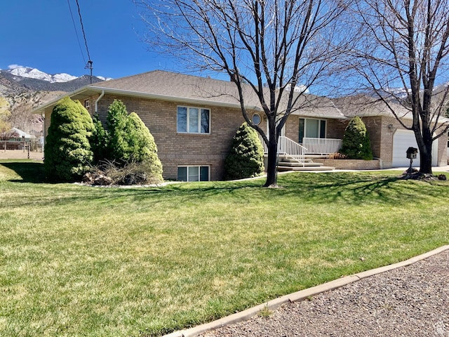 view of front of house featuring a mountain view, a front yard, and a garage
