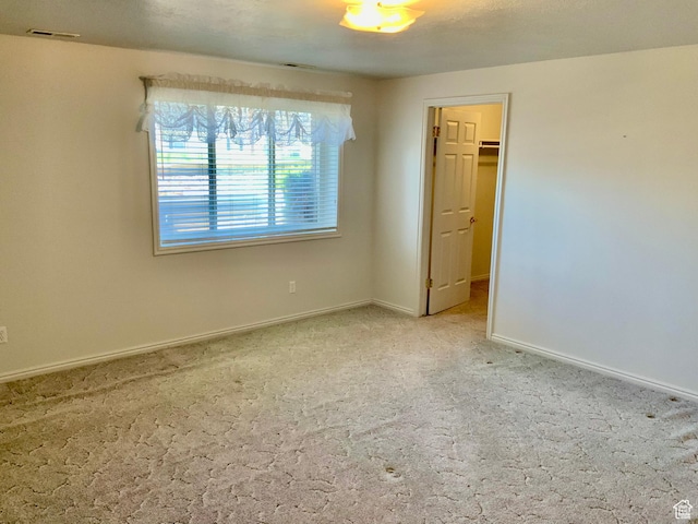 unfurnished bedroom with a walk in closet and carpet flooring