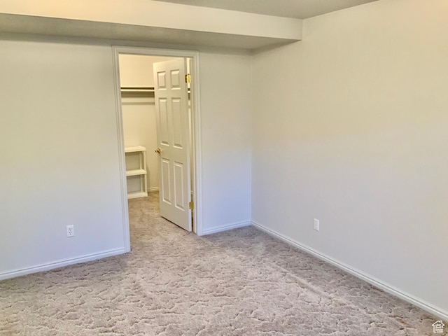 unfurnished bedroom featuring light carpet, a closet, and a walk in closet