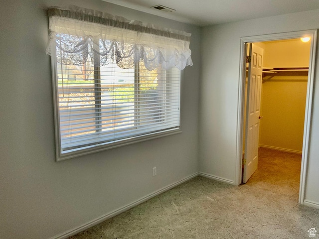 unfurnished bedroom featuring a closet, a spacious closet, and light colored carpet